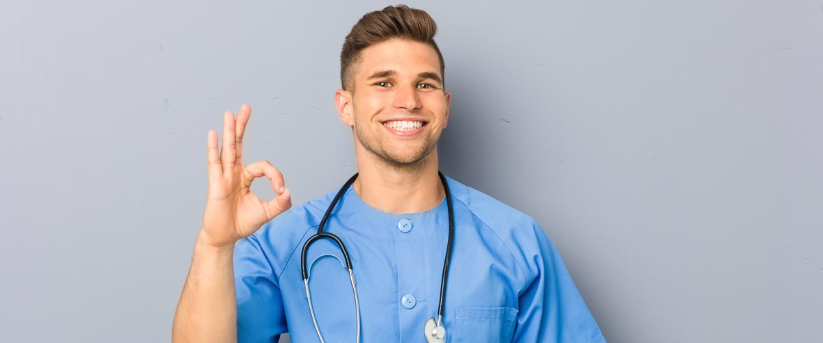 Junge Krankenpflegefachkrafte grinst und zeigt Okay Zeichen