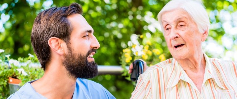 Altenpfleger unterhält sich mit Seniorin im Heim
