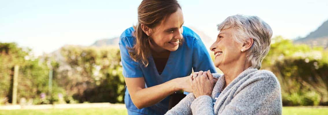 Altenpflegerin mit Patientin im Rollstuhl