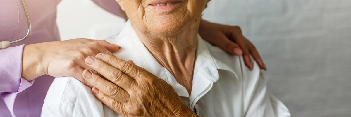 Pflegerin in Zeitarbeit berührt die Schulter einer alten Frau