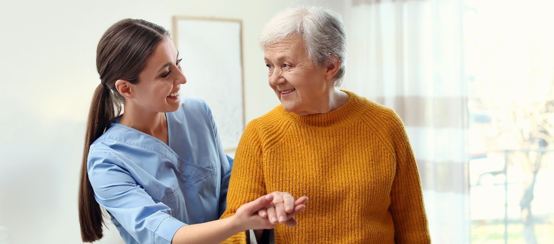 Mitarbeiterin in der carecompany GmbH Geriatrie hilft älterer Frau